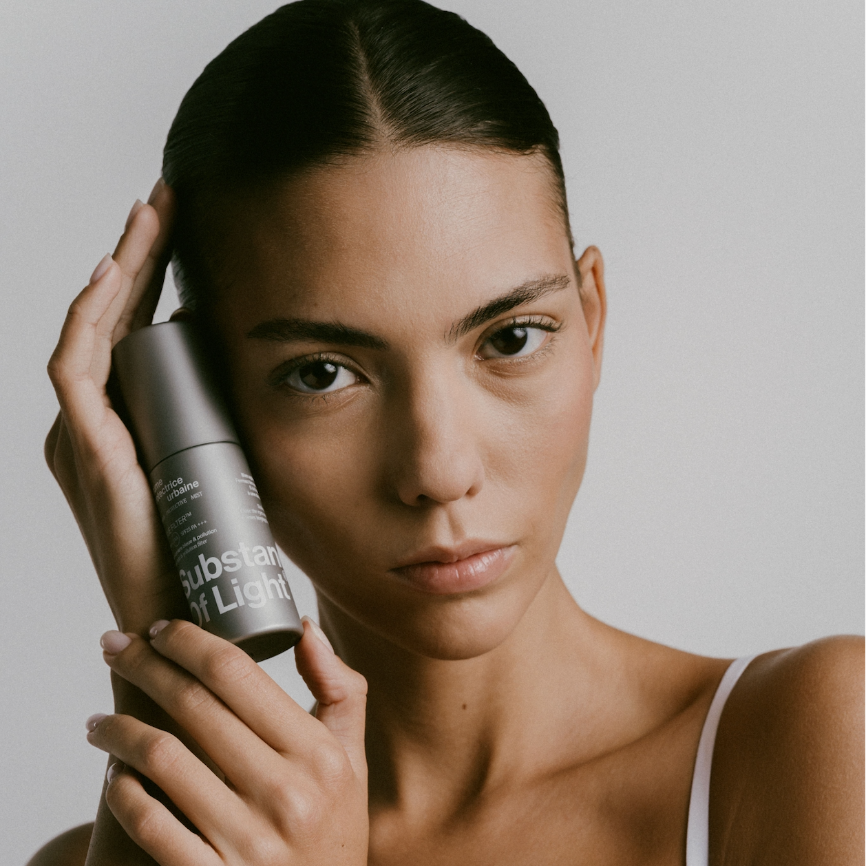 Femme tenant la brume protectrice urbaine SPF25 PA+++ dans ses mains