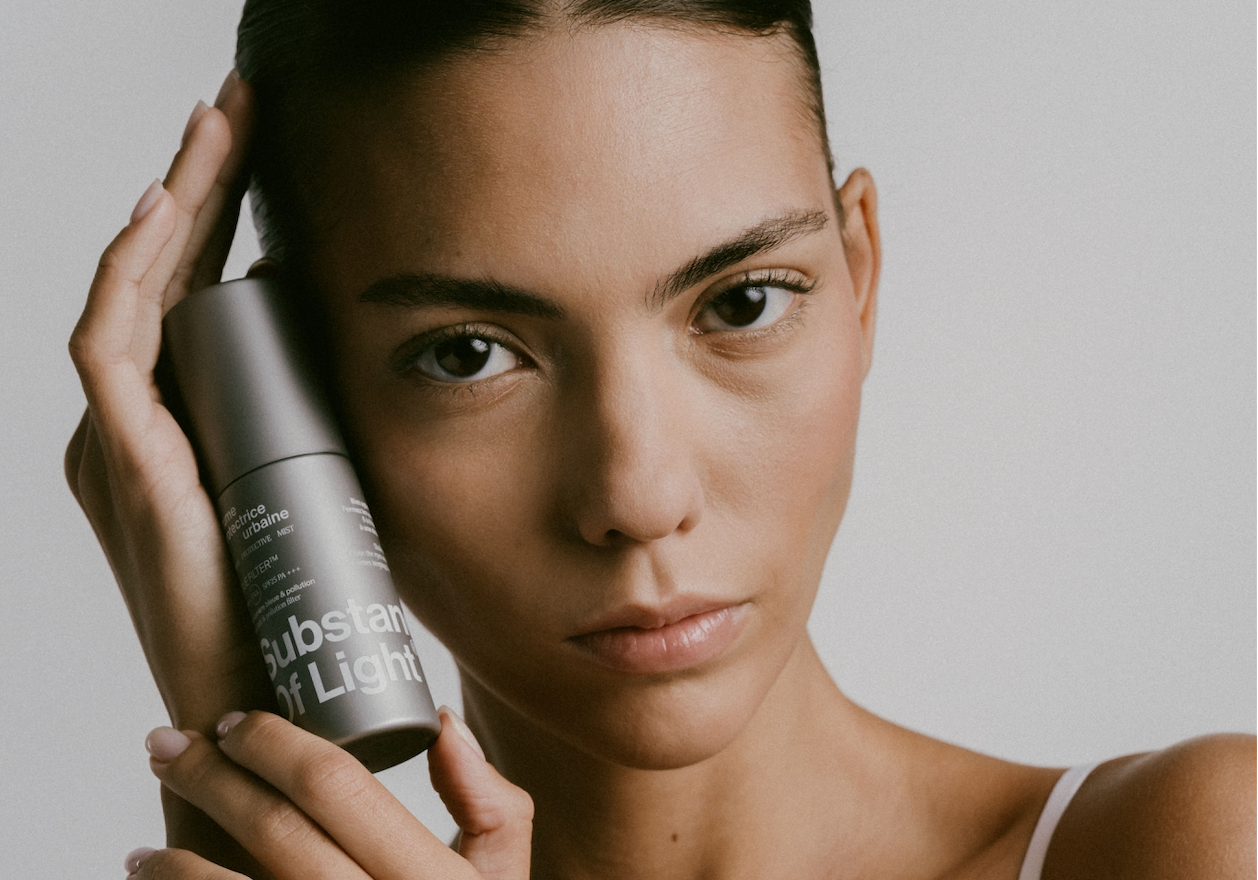 Femme tenant la brume protectrice urbaine SPF25 PA+++ dans ses mains