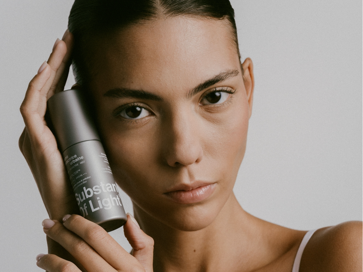 Femme tenant la brume protectrice urbaine SPF25 PA+++ dans ses mains